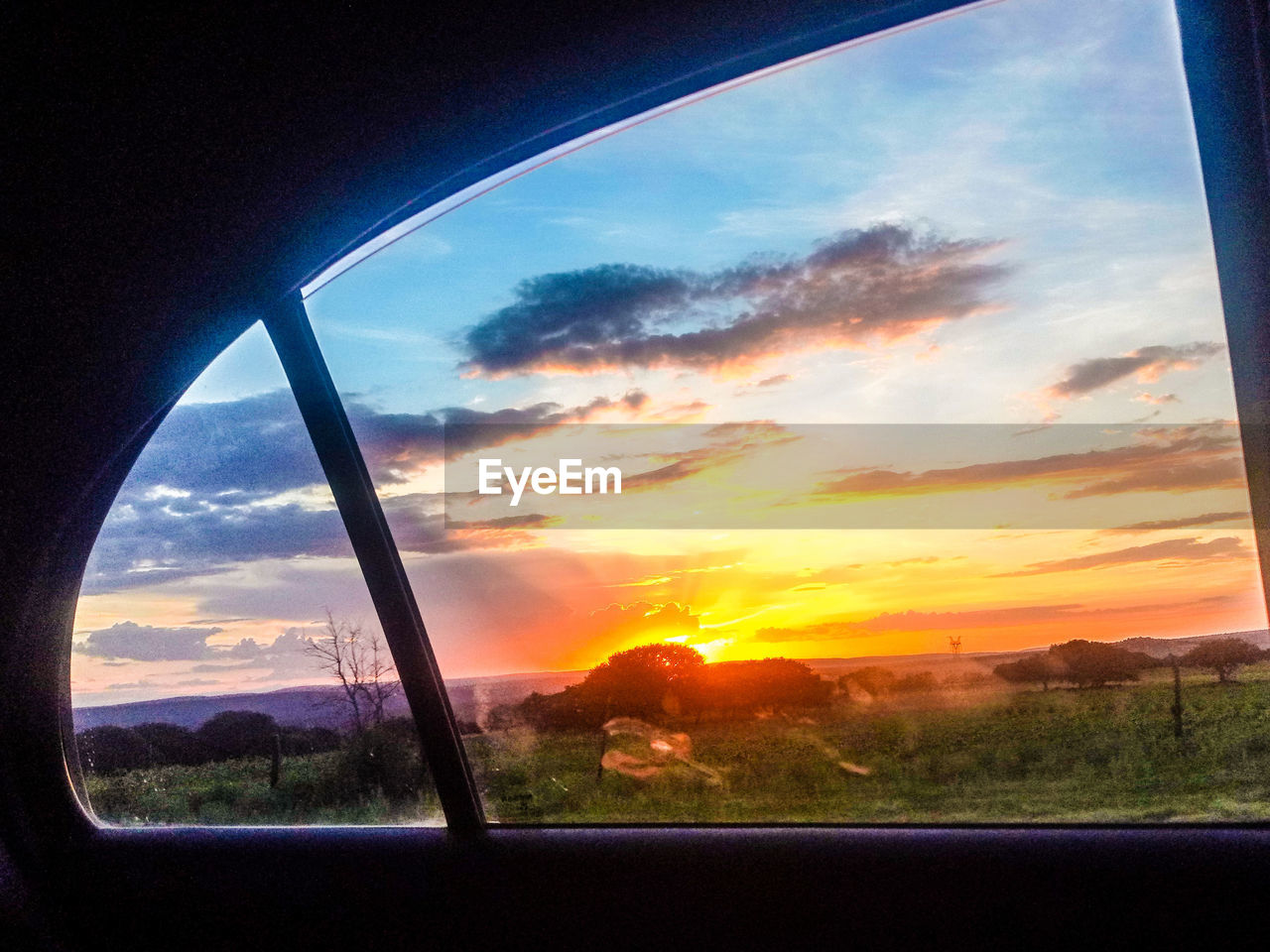 LANDSCAPE SEEN THROUGH WINDOW DURING SUNSET