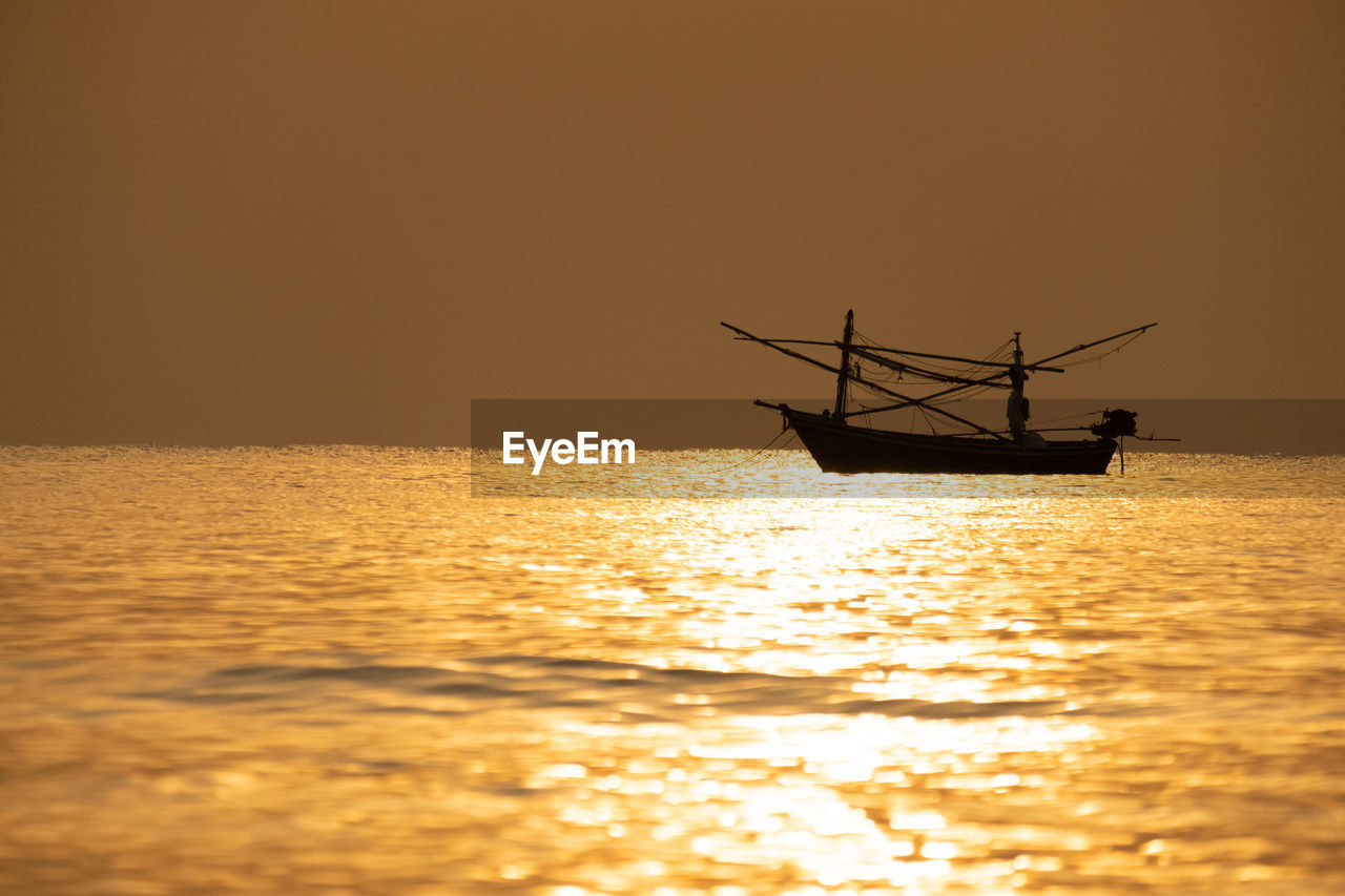 Silhouette boat in sea against sky during sunset