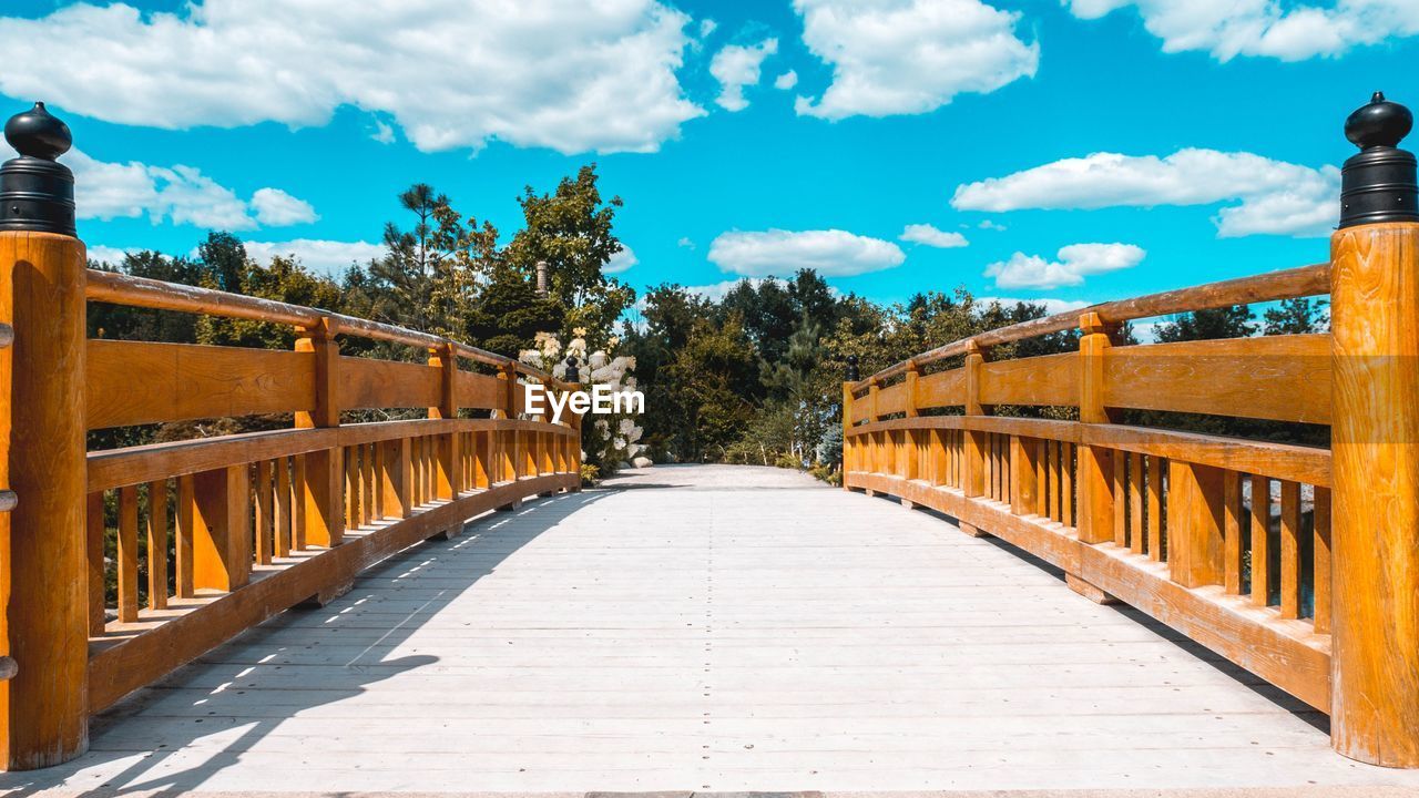 Footbridge amidst trees against sky