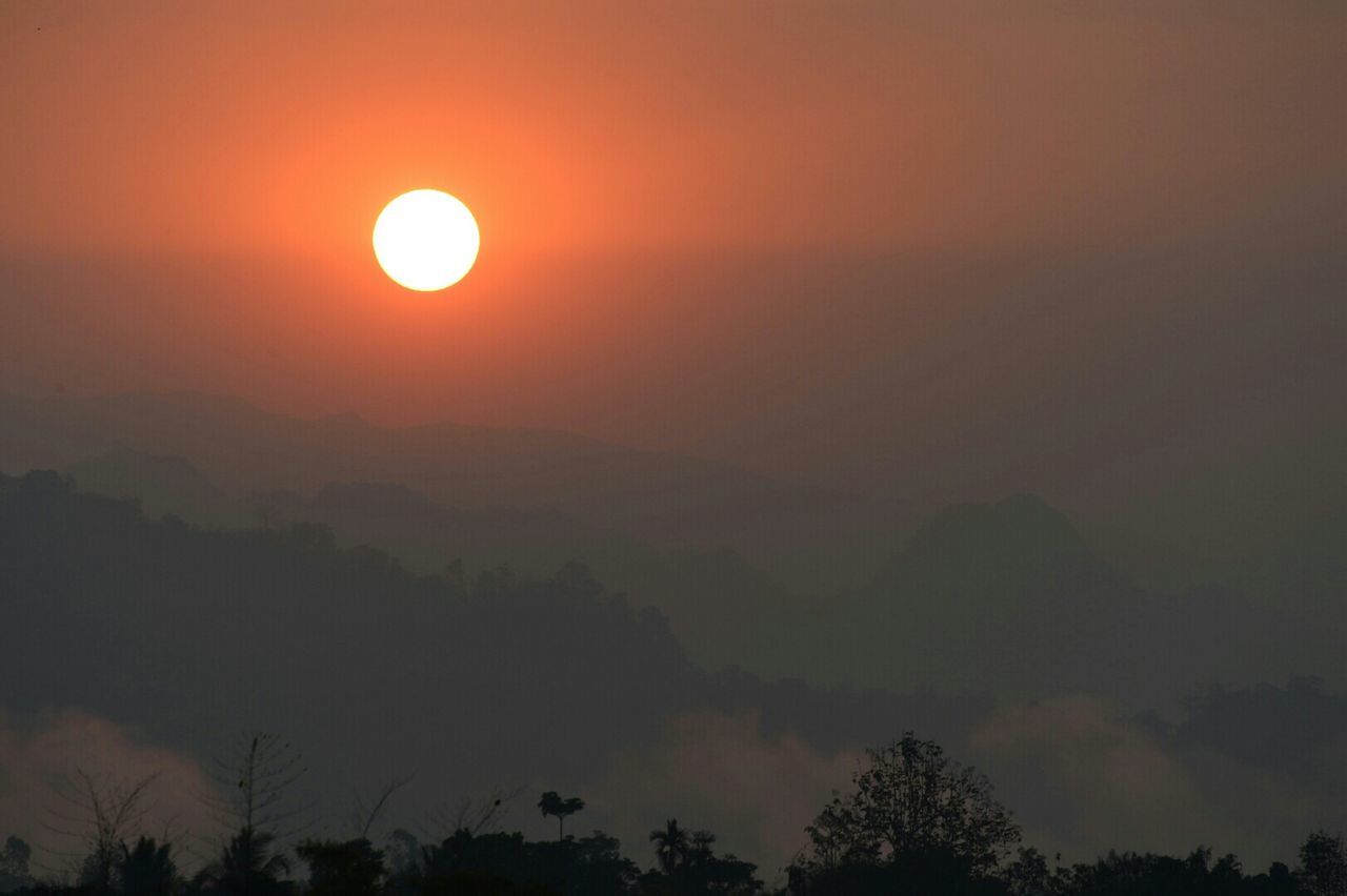 Scenic view of mountains against sky during sunset during foggy weather