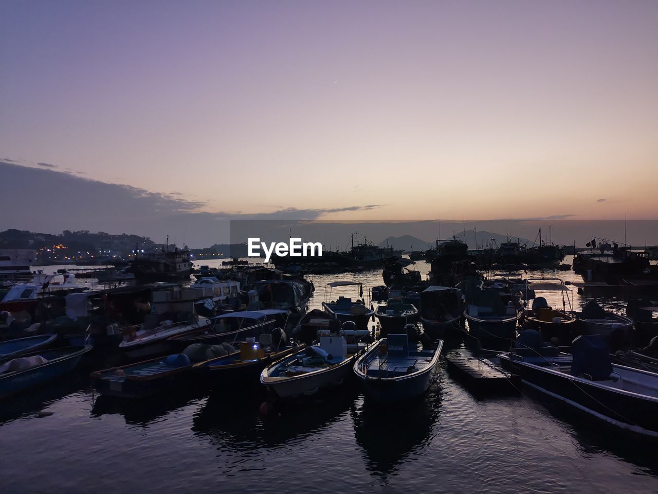 Boats moored at harbor during sunset