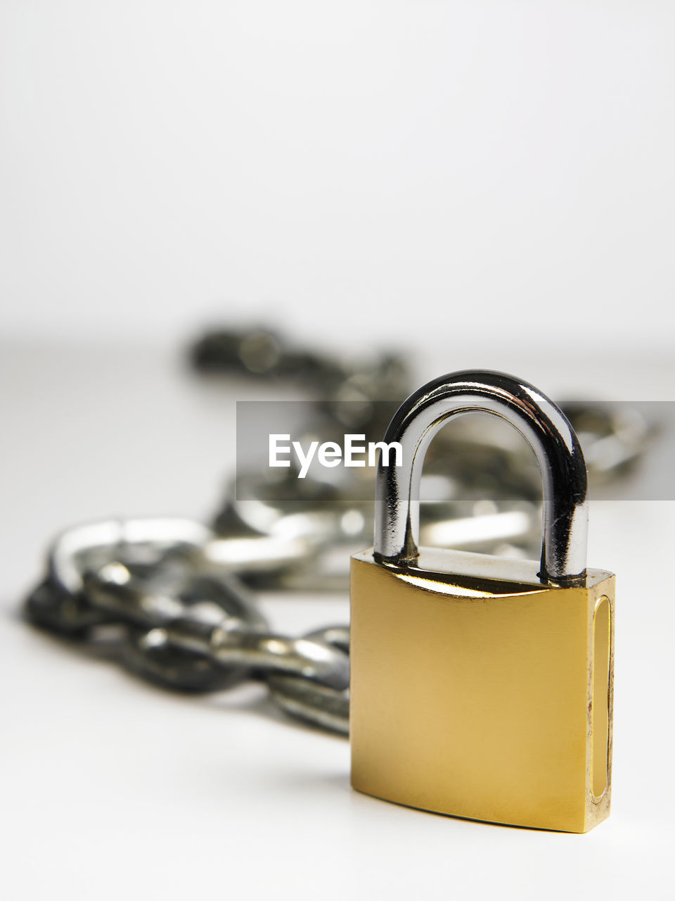 Close-up of padlock with chain over white background