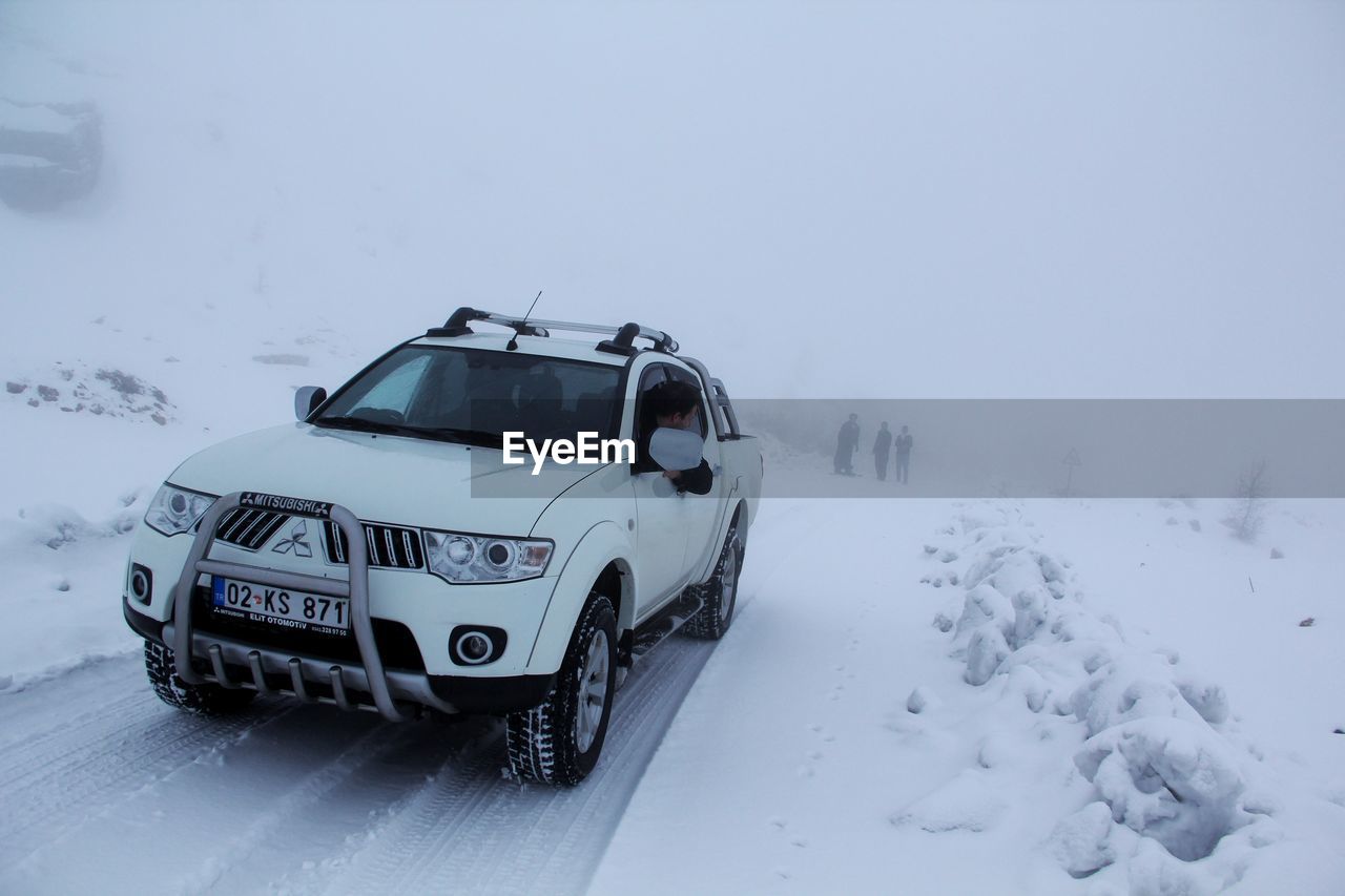 VIEW OF CAR ON SNOW COVERED ROAD