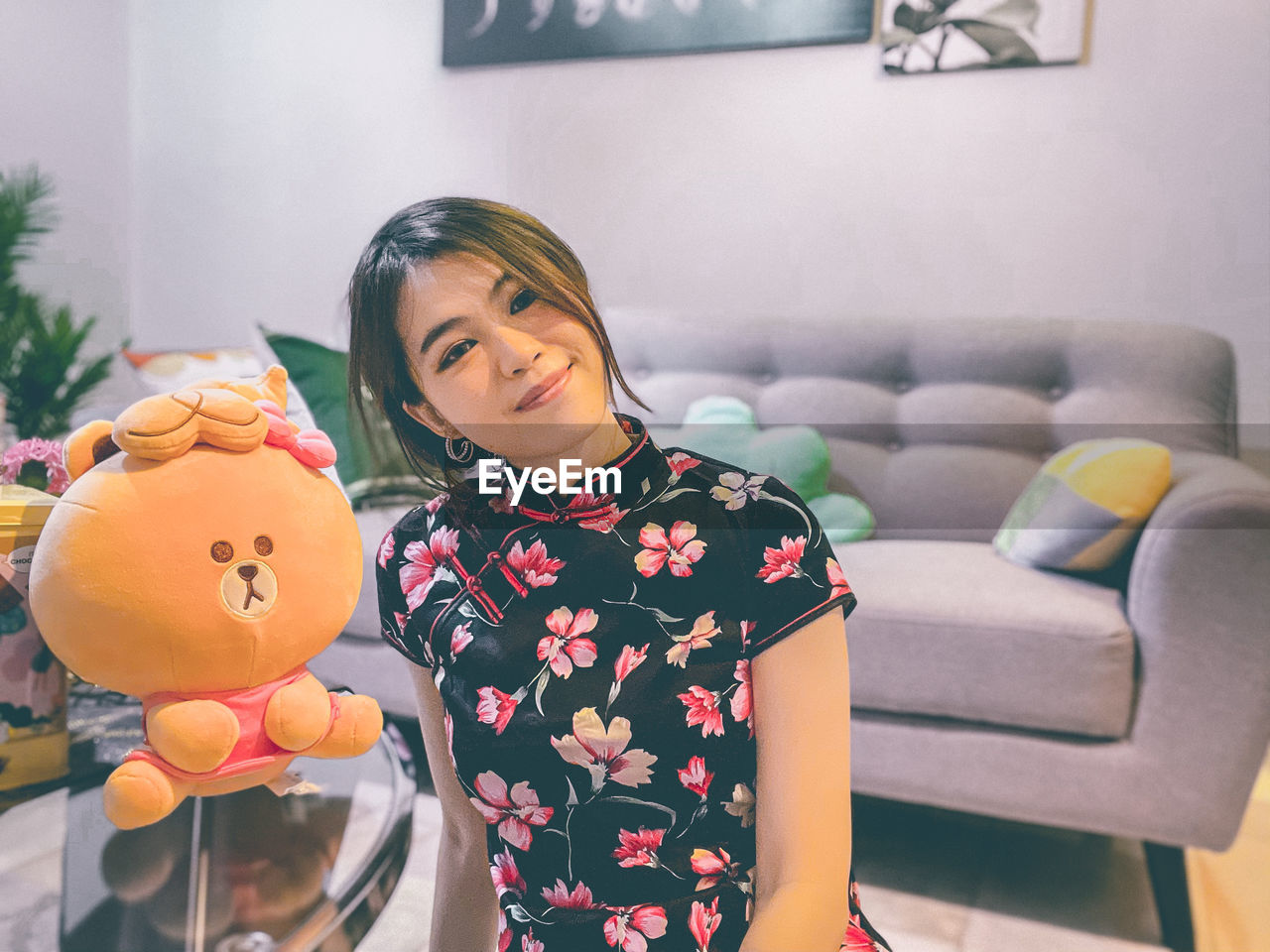 Smiling woman with stuffed toy at home