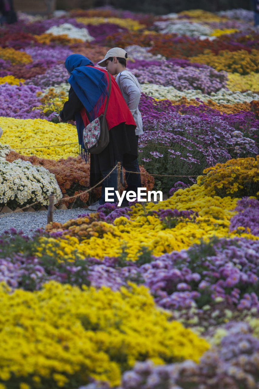 Mother with son standing by flowers in park