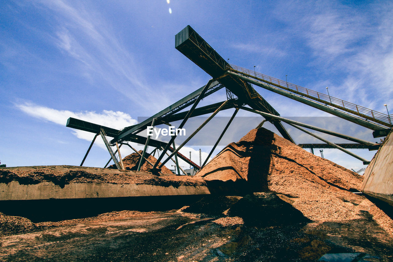 Low angle view of metallic structure at industry against sky