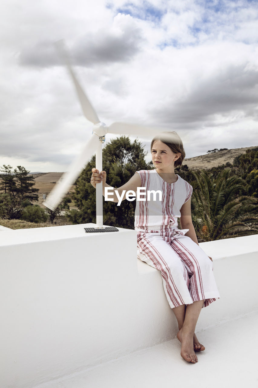 Girl looking at small wind turbine on white wall