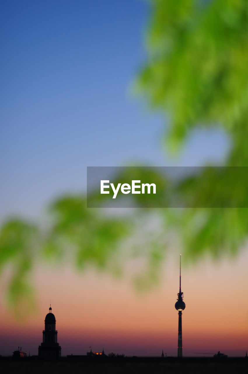 Illuminated fernsehturm against sky during sunset