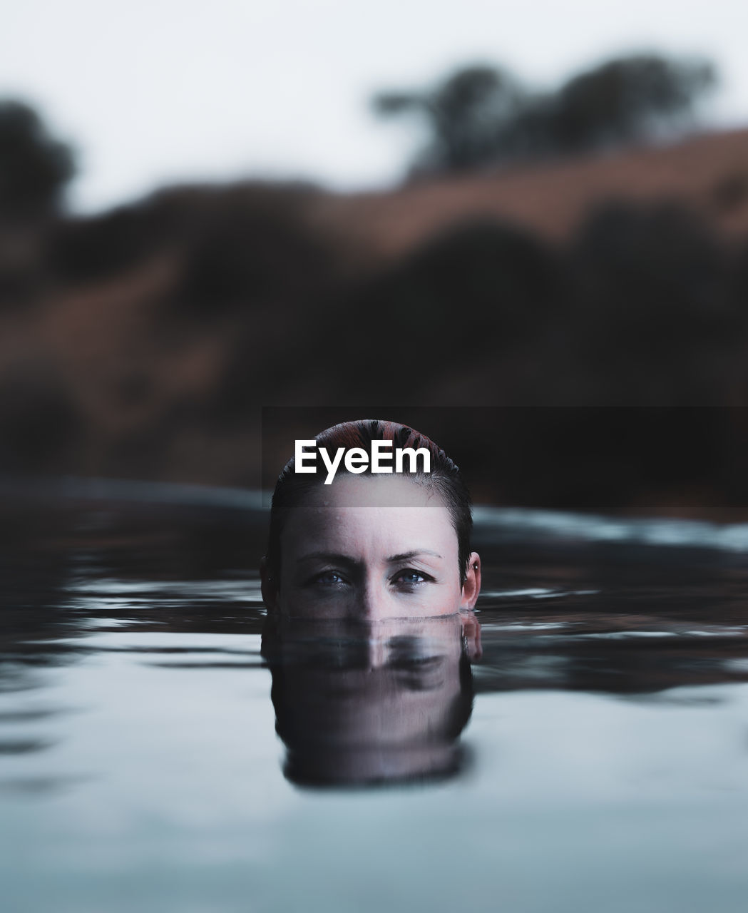 Portrait of young female with short hair swimming in pool with face partially submerged 