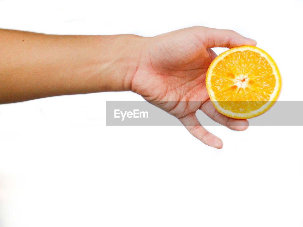 CROPPED IMAGE OF HAND HOLDING ORANGE SLICE