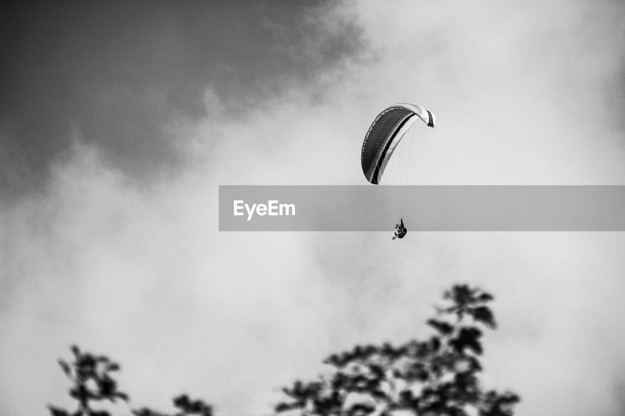 Low angle view of man paragliding against sky