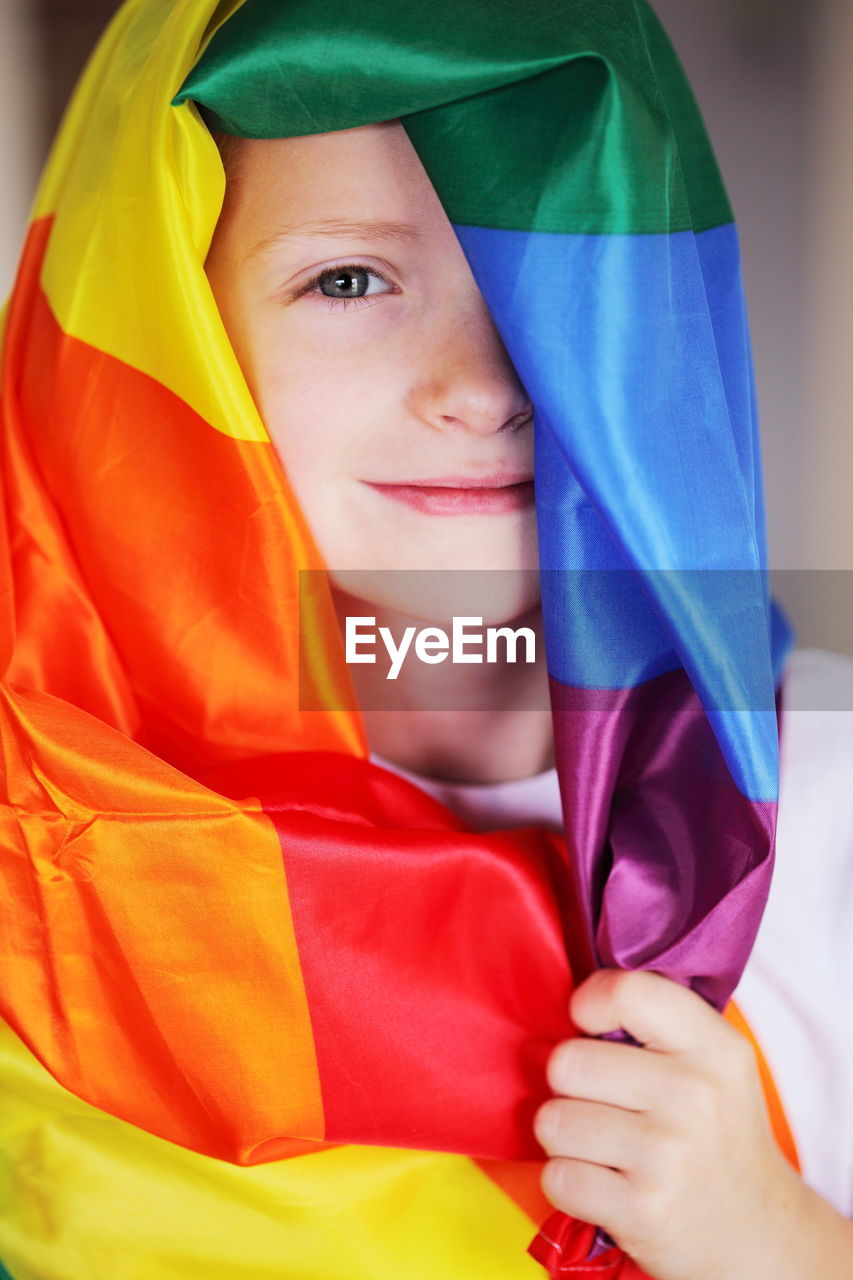 Portrait of boy covering himself with colorful scarf