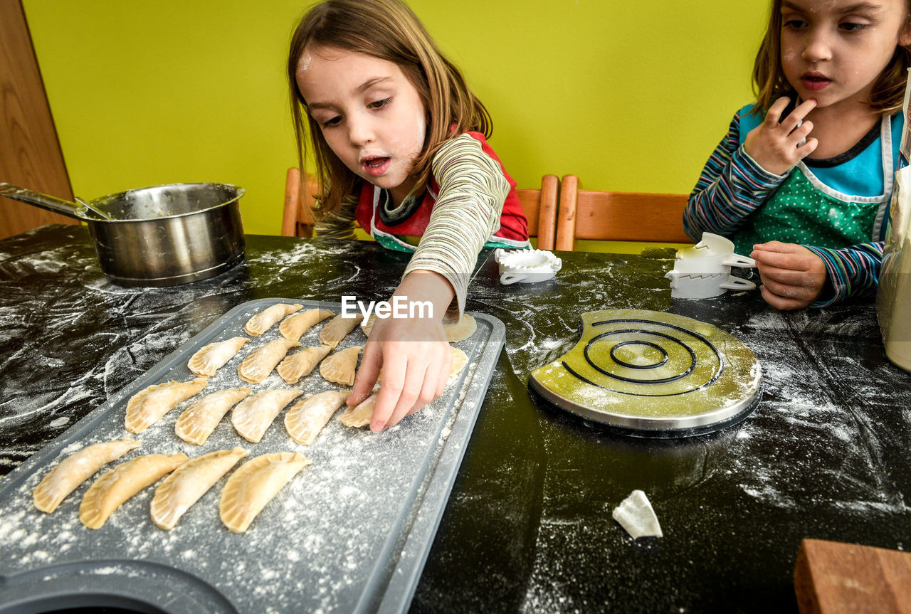 Sisters preparing food in kitchen at home