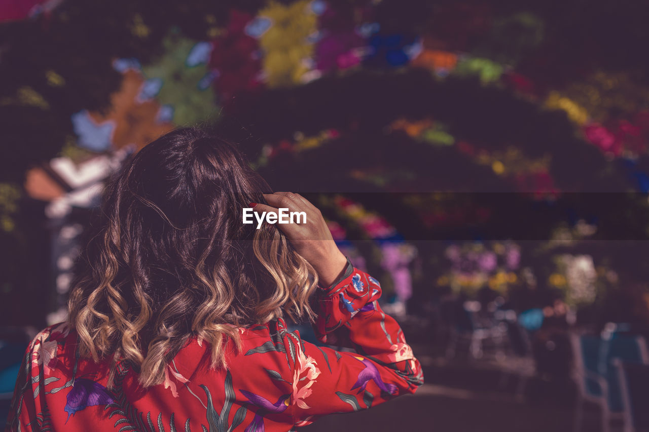 Rear view of woman with brown wavy hair in city