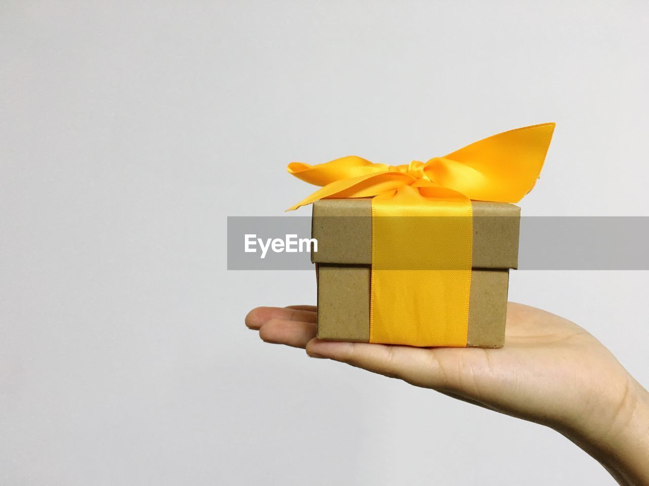 Cropped hand of person holding gift box against white background