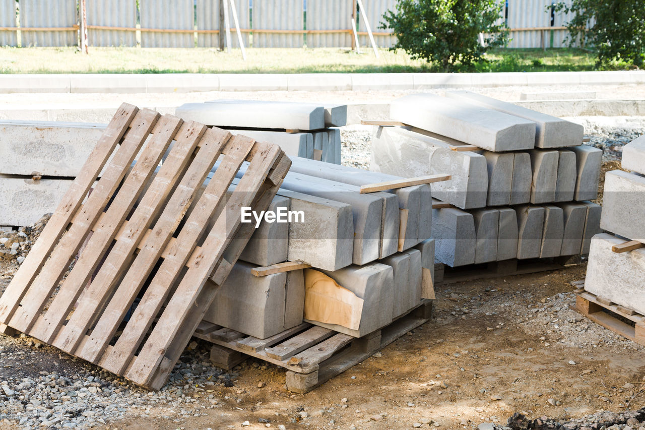 Reinforced concrete blocks neatly stacked on the territory of a fenced construction site, 