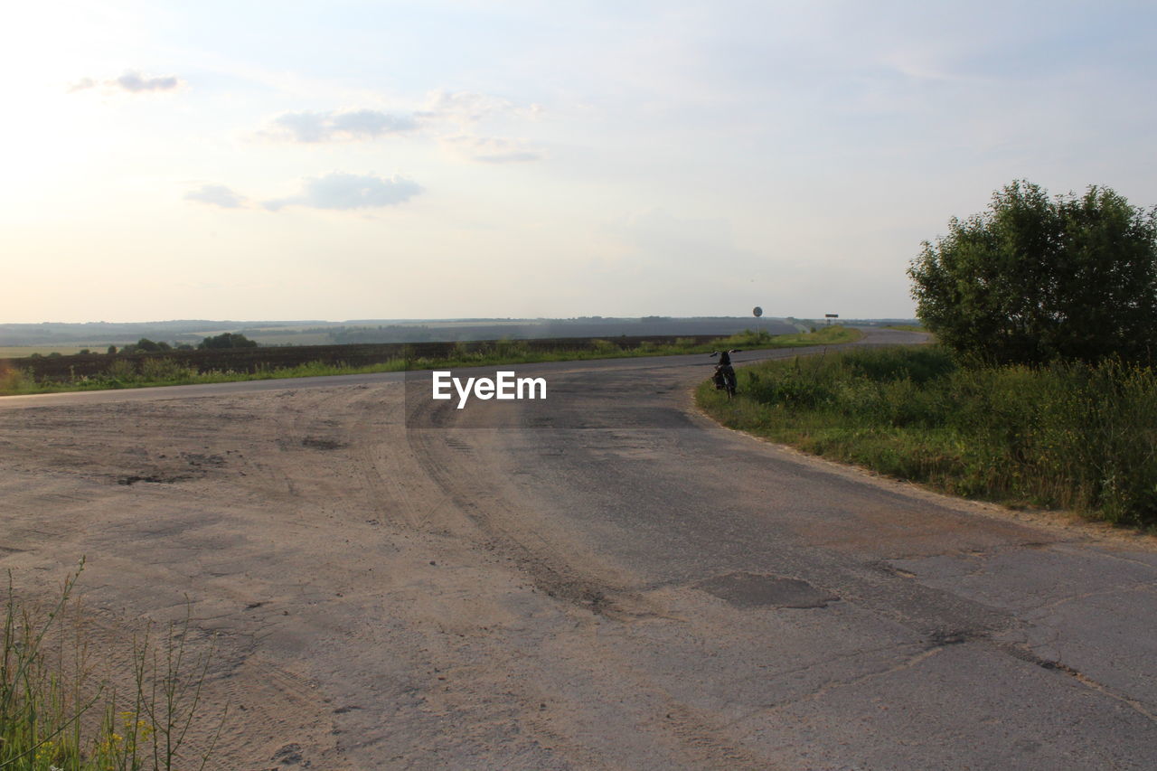 ROAD PASSING THROUGH FIELD AGAINST SKY