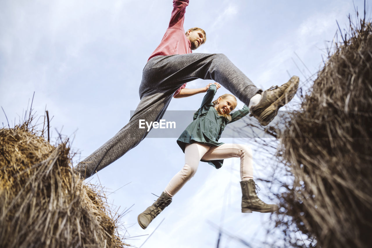 Father and daughter jumping over hay bales with excitement