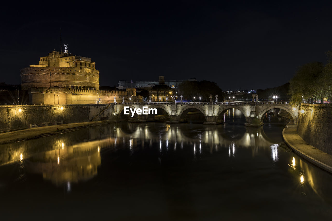 ILLUMINATED BRIDGE OVER RIVER AGAINST SKY