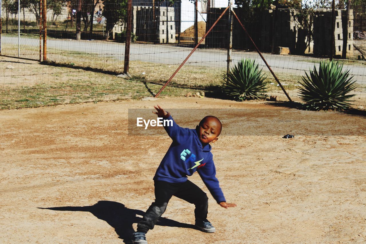 Full length of boy playing on field during sunny day