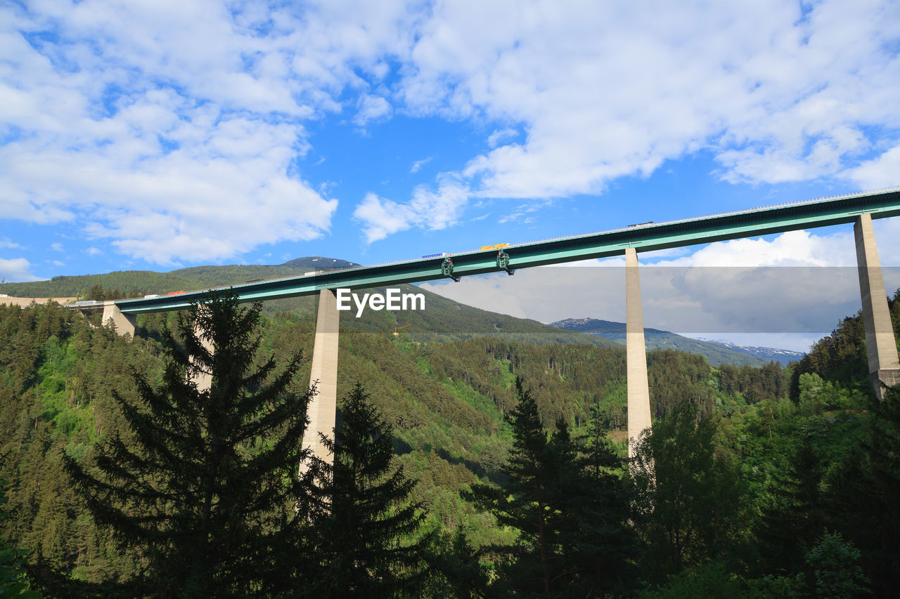 LOW ANGLE VIEW OF BRIDGE AGAINST TREES AND SKY