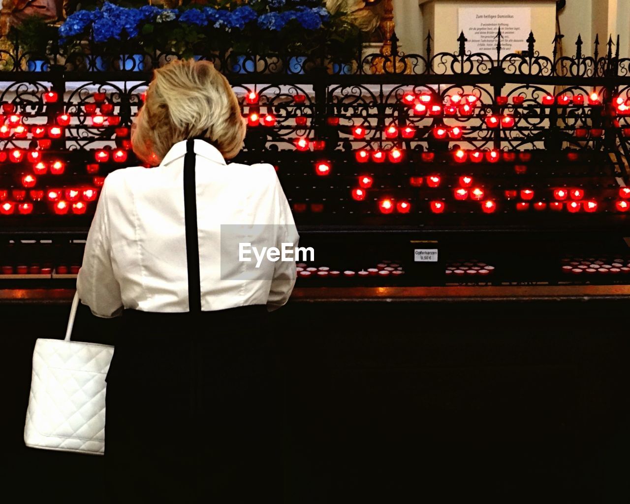 Rear view of woman praying in church at night