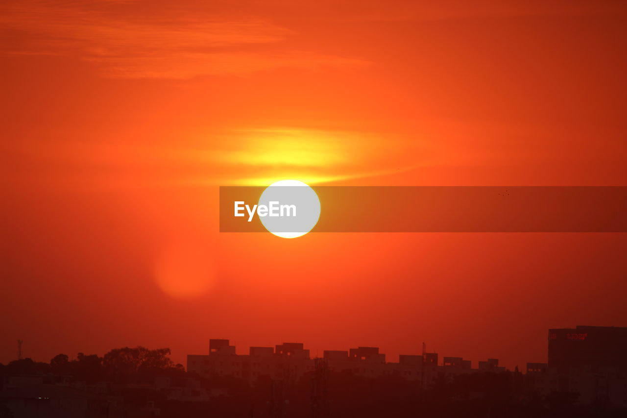 sky, sunset, afterglow, horizon, city, architecture, sun, building exterior, orange color, nature, built structure, urban skyline, cityscape, sunlight, beauty in nature, dawn, landscape, no people, dramatic sky, building, scenics - nature, astronomical object, cloud, red sky at morning, silhouette, outdoors, tranquility, environment, evening, idyllic, romantic sky, tranquil scene, travel destinations, red, residential district, orange, city life, geometric shape, yellow, atmospheric mood, skyscraper, office building exterior