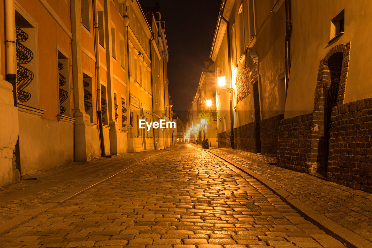 Illuminated street amidst buildings at night