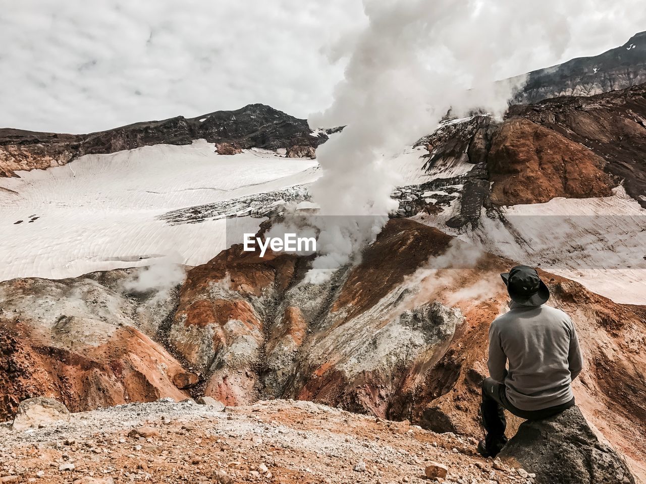 Man looking at volcano mountain against sky