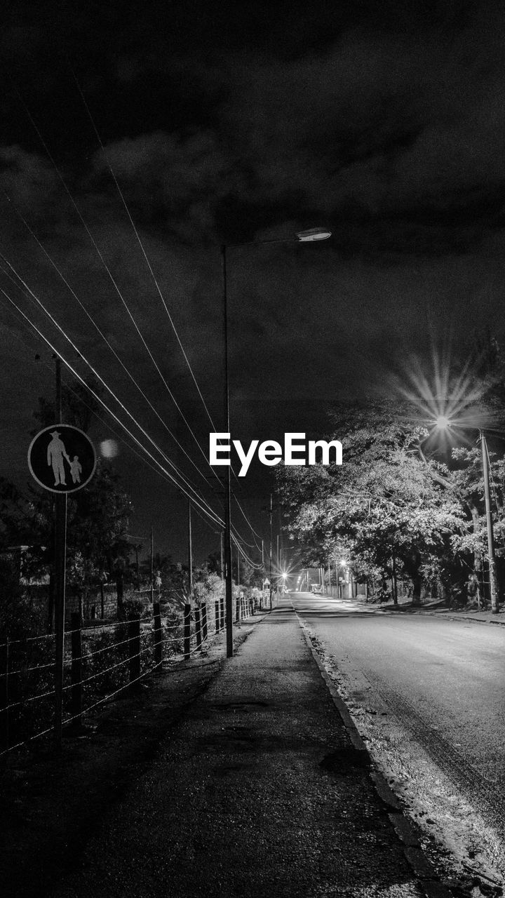 ROAD BY ILLUMINATED STREET LIGHT IN CITY