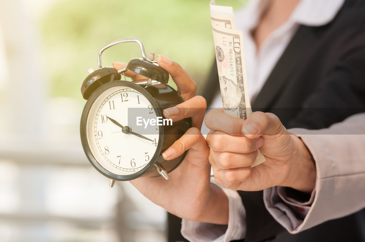 CLOSE-UP OF MAN HAND HOLDING CLOCK