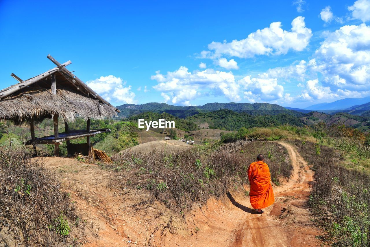 REAR VIEW OF MAN ON FIELD AGAINST MOUNTAIN