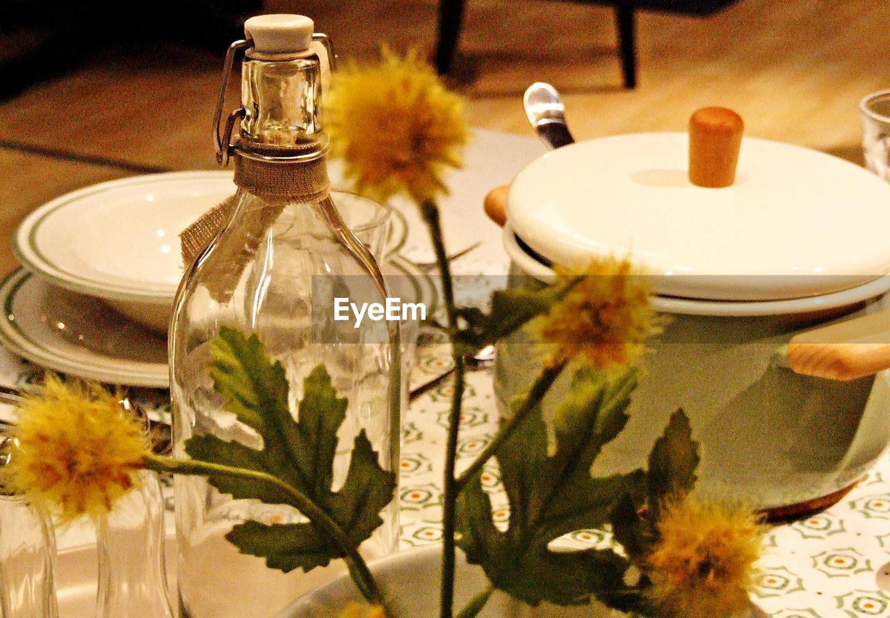 Close-up of flowers by bottles and container on table