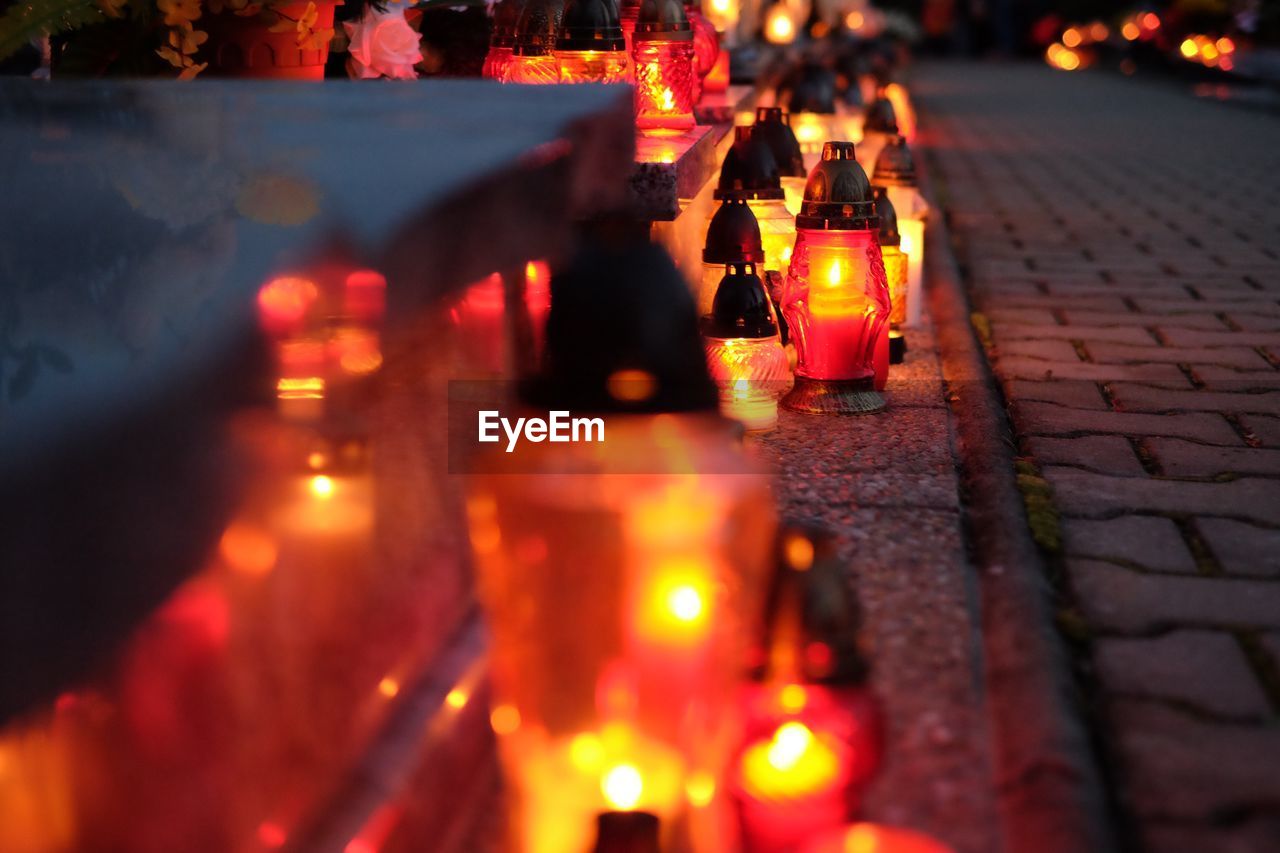 CLOSE-UP OF ILLUMINATED LIGHT BULBS ON SIDEWALK