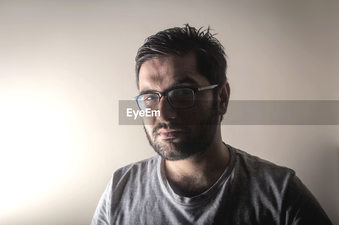 Portrait of young man wearing eyeglasses against gray background