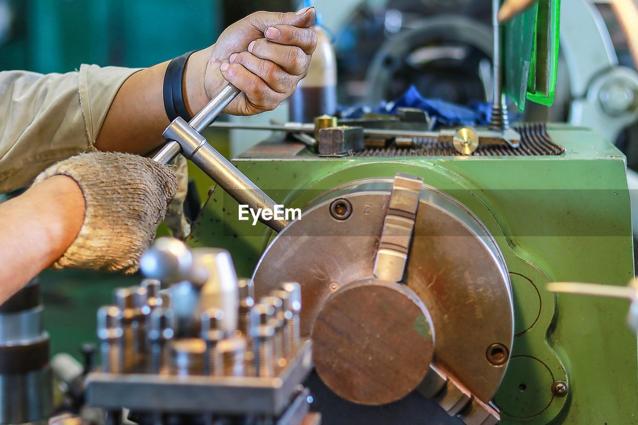 Cropped hands of worker operating equipment in workshop