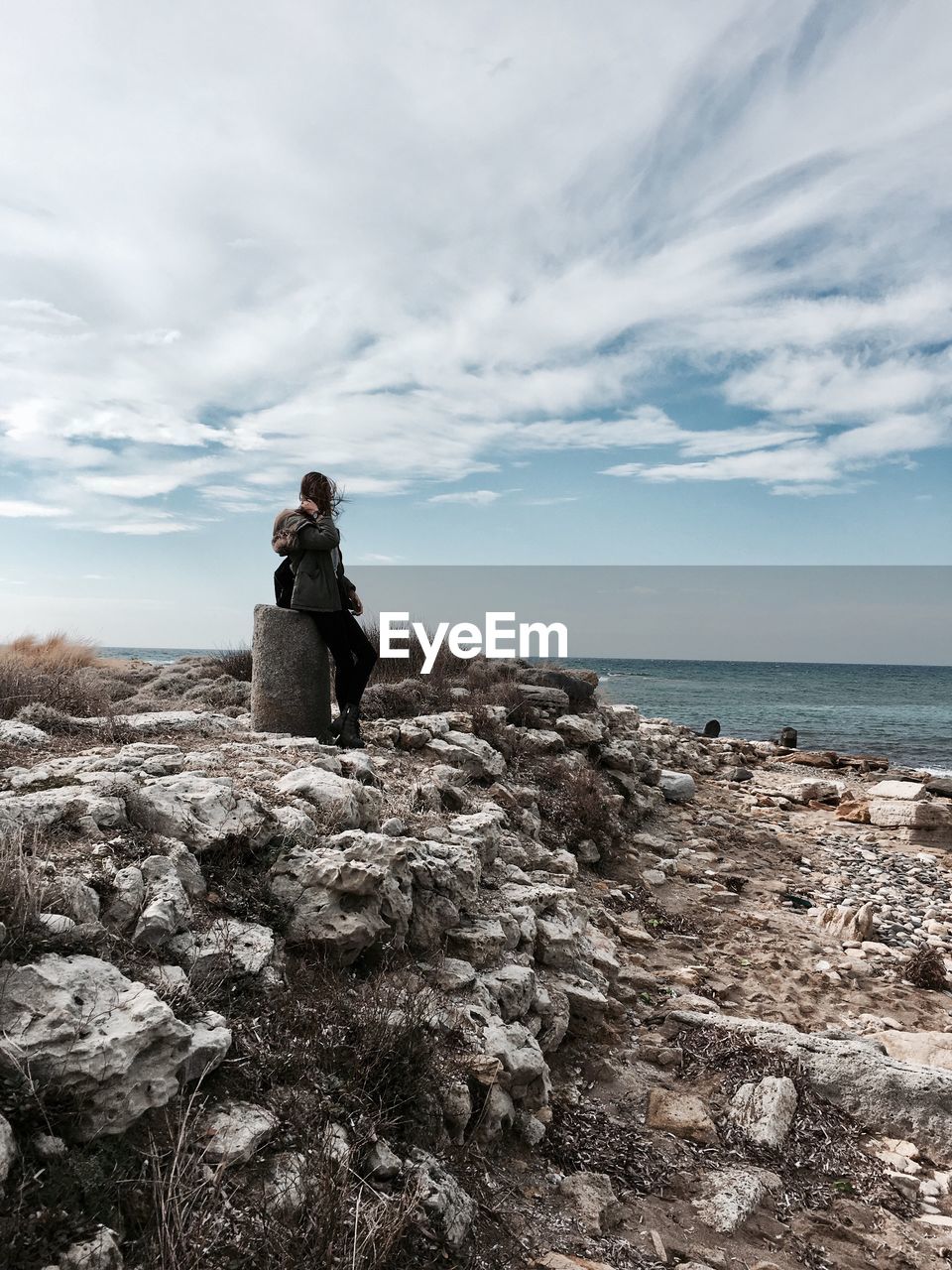 Woman sitting on rock against sea at beach