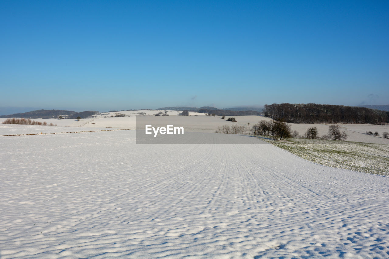 Snow landscape with fields and fog in the valley and with blue sky in spessart, bavaria, germany