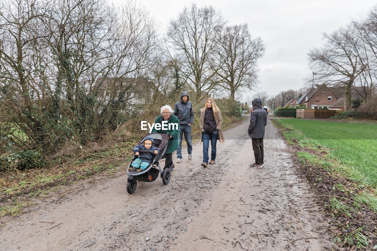 Family on dirt road by bare trees