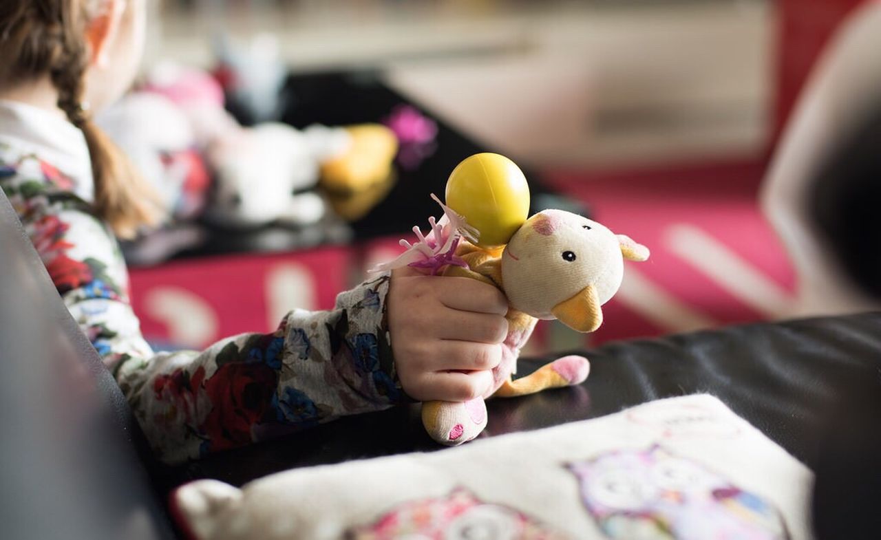 Cropped image of girl holding puppet by sofa at home