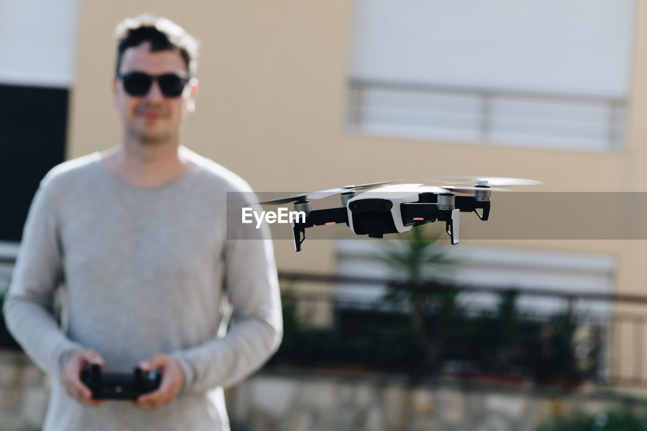 Man flying drone against building