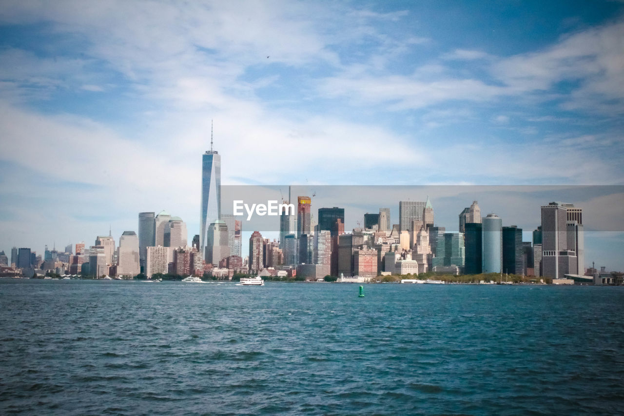 Scenic view of cityscape by sea against sky