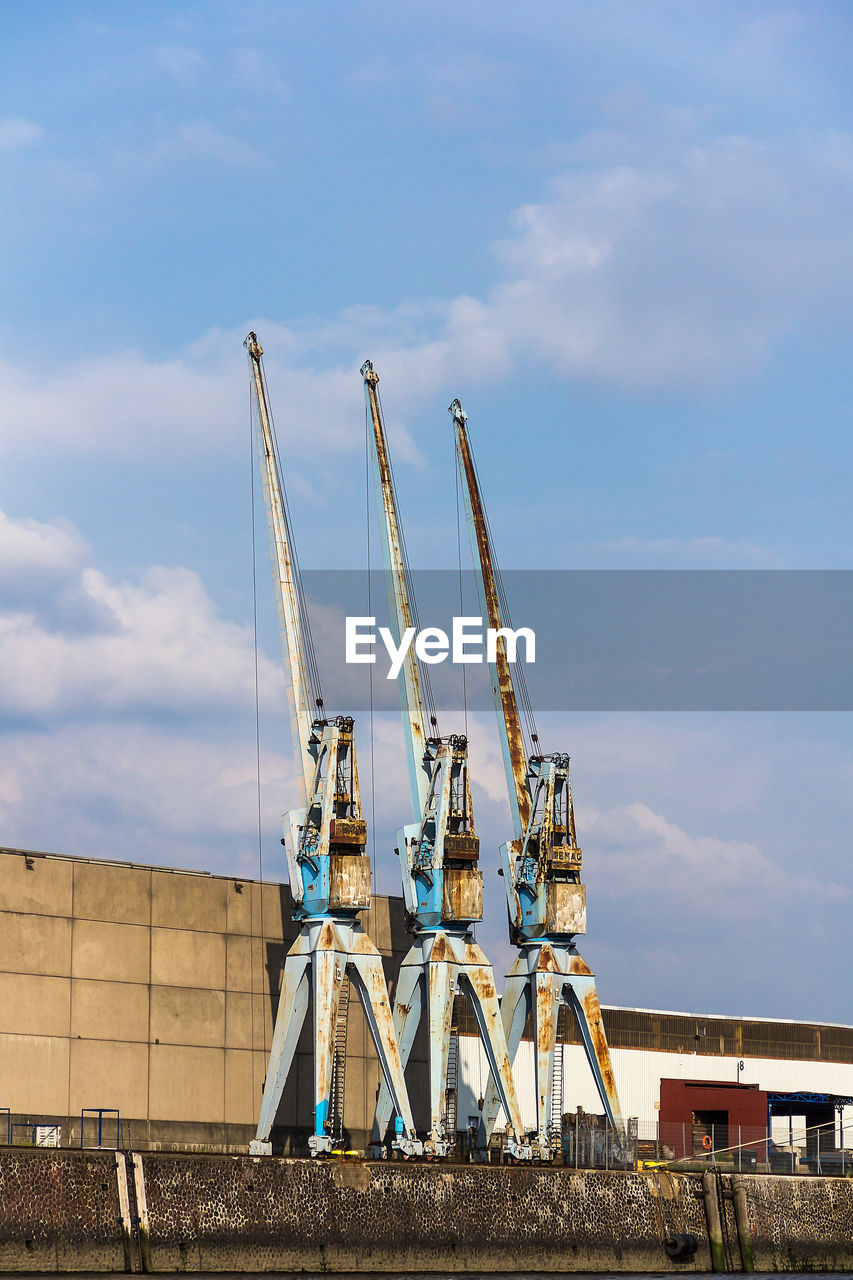 LOW ANGLE VIEW OF CRANES AGAINST SKY