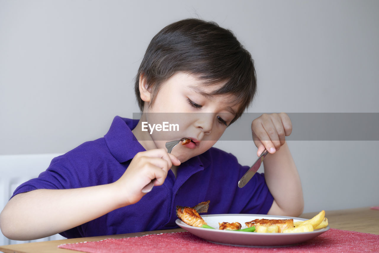 Cute boy eating food at home