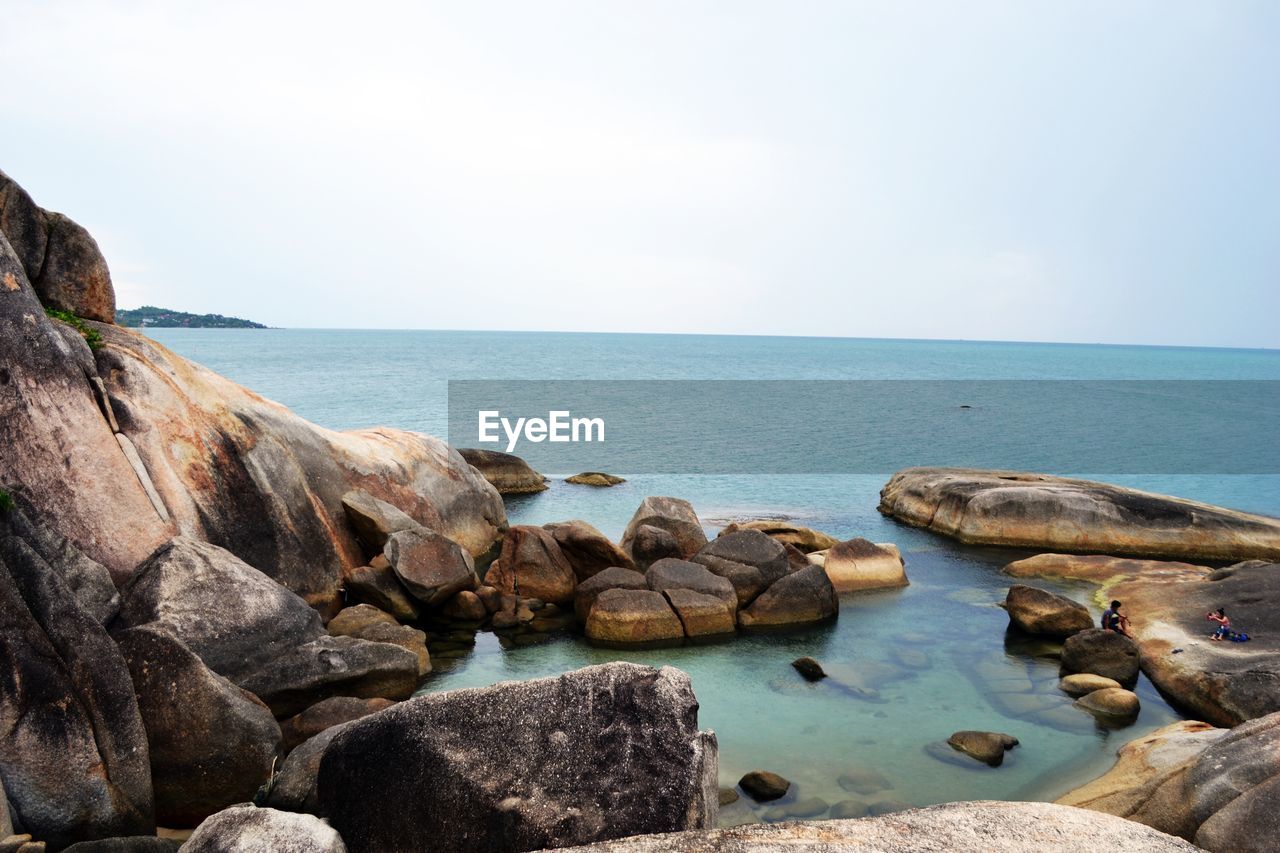 Rocks by sea against clear sky