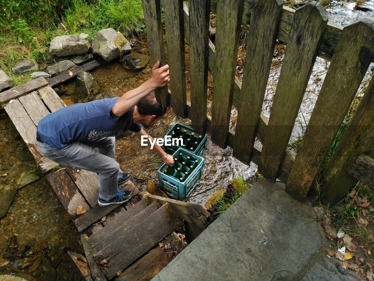 High angle view of man picking bottles from crate on river