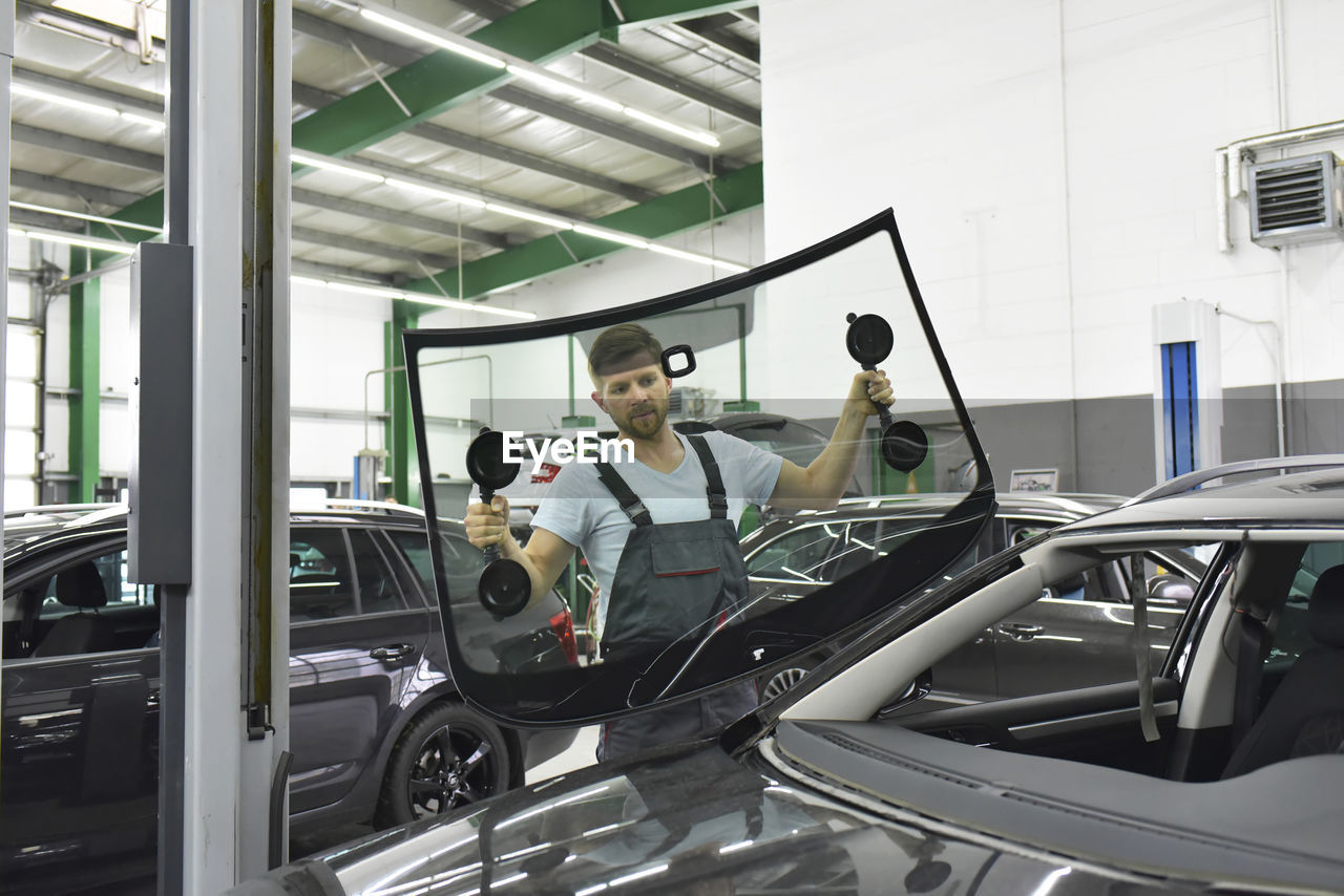 Car mechanic in a workshop changing car window