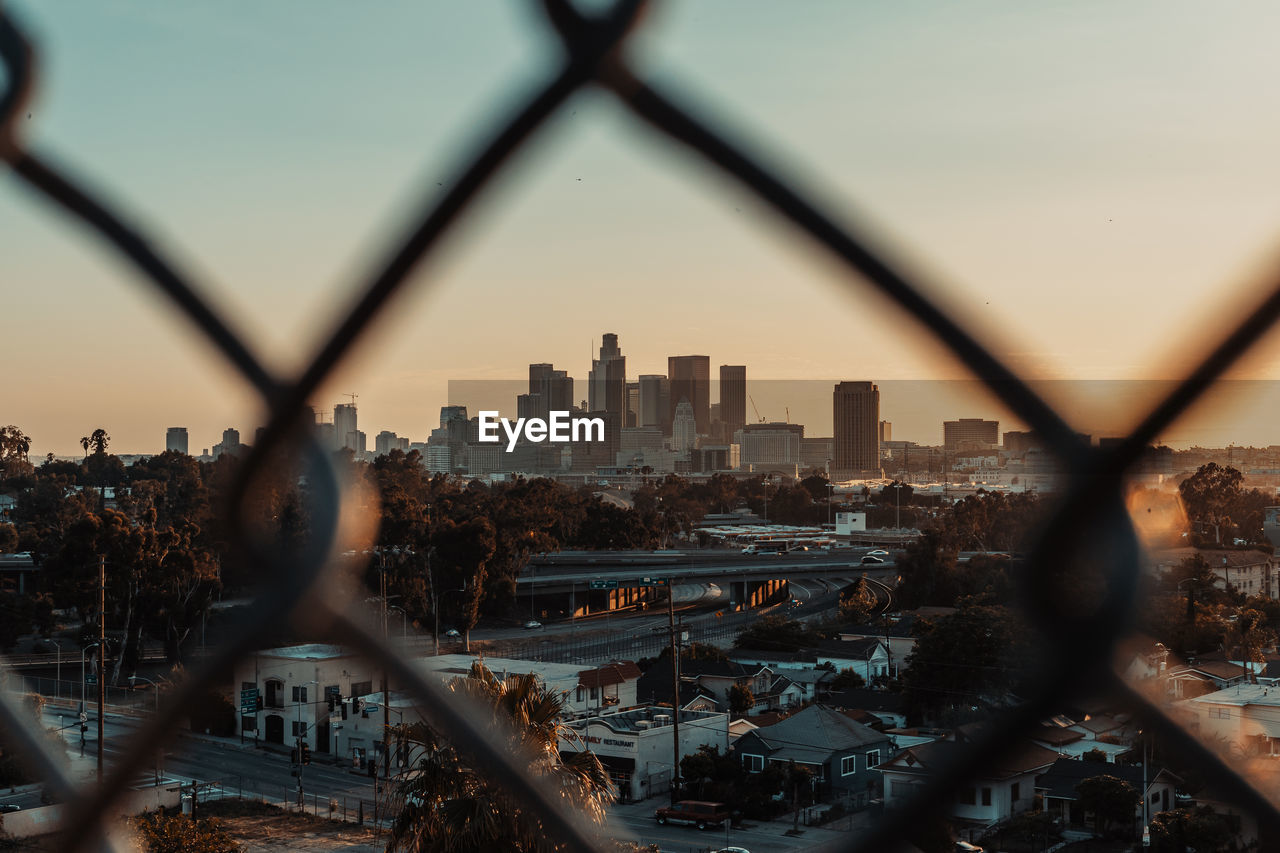 VIEW OF CITYSCAPE THROUGH CHAINLINK FENCE