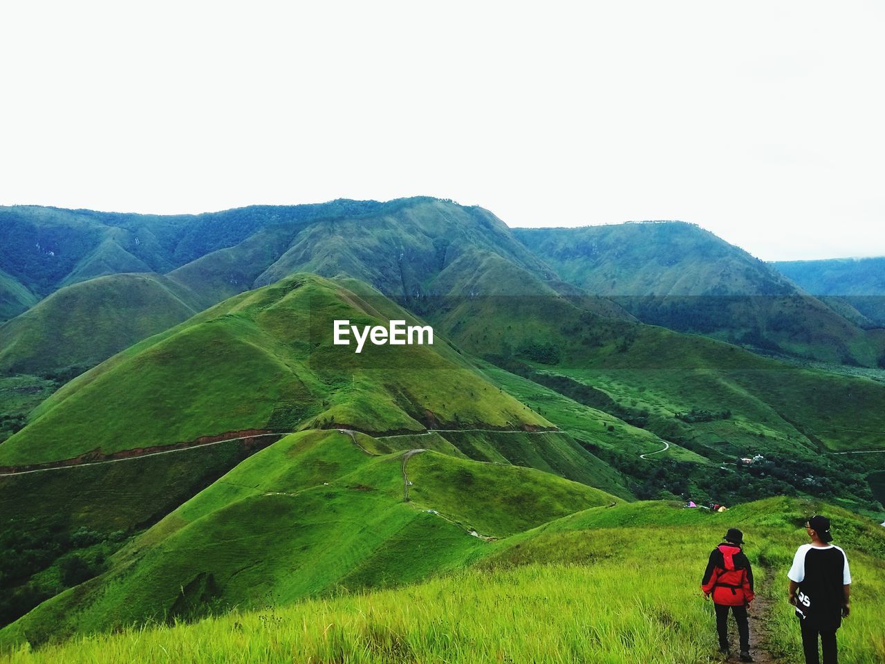 REAR VIEW OF PEOPLE ON MOUNTAIN AGAINST SKY