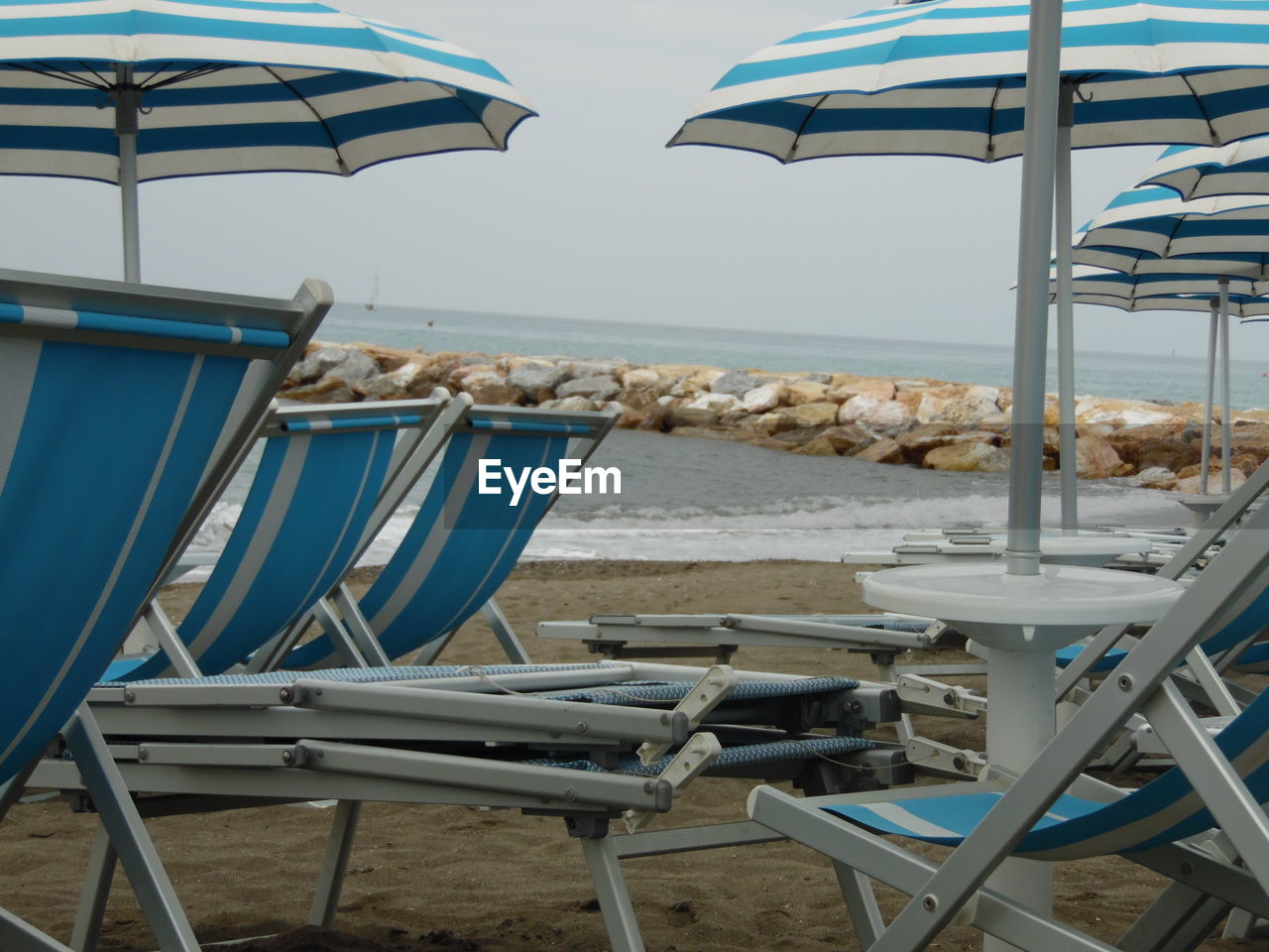 Chairs and table on beach against clear sky